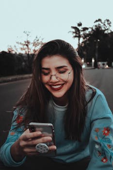 A young woman sitting on a road, smiling while using her smartphone in Ciudad del Este, Paraguay.